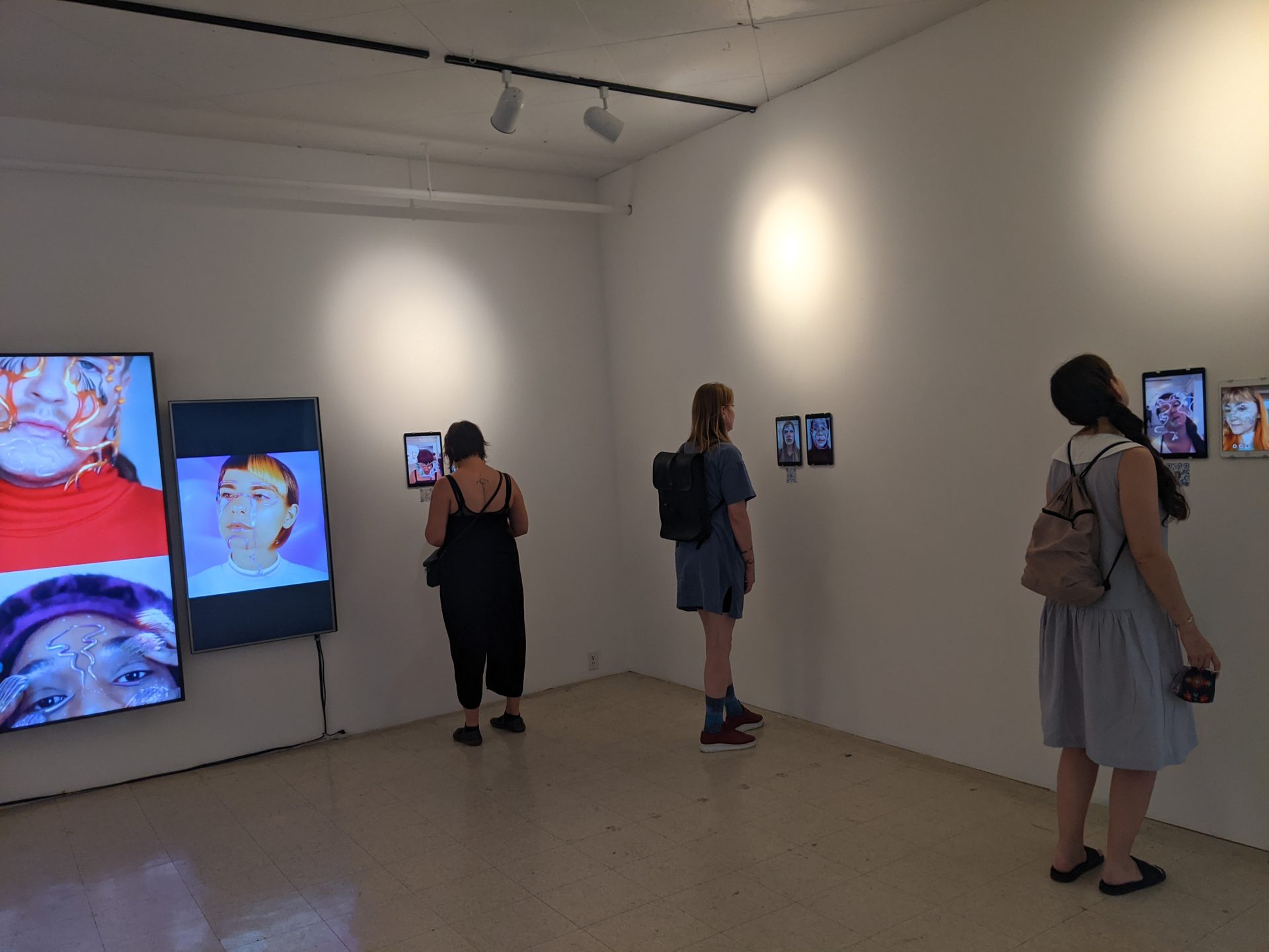 Alpha Manifestations — visitors walking through gallery at Art Mûr, large screens displaying digital cosmetics works