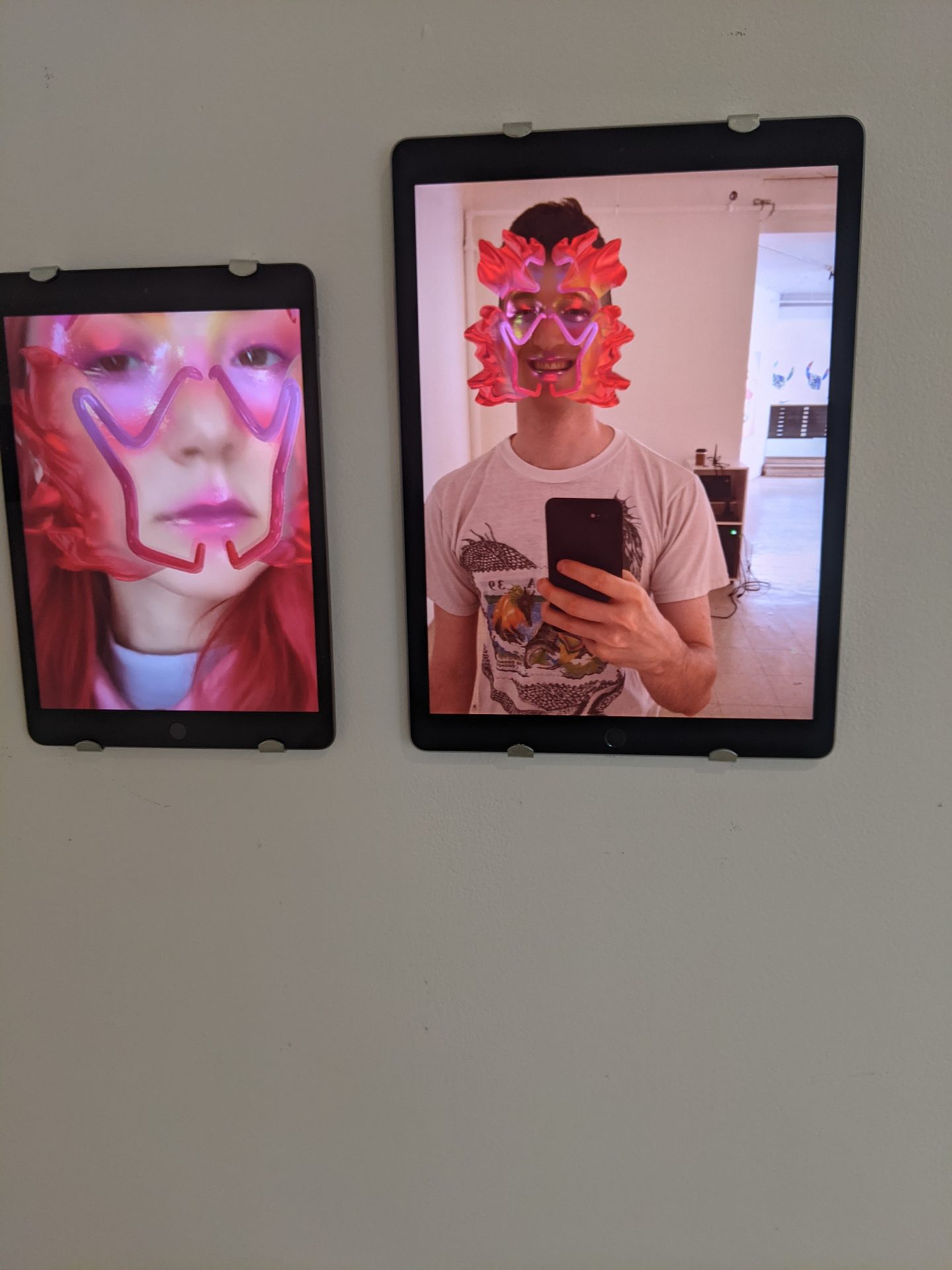 Alpha Manifestations — iPad screens displaying visitors wearing AR digital cosmetics filters