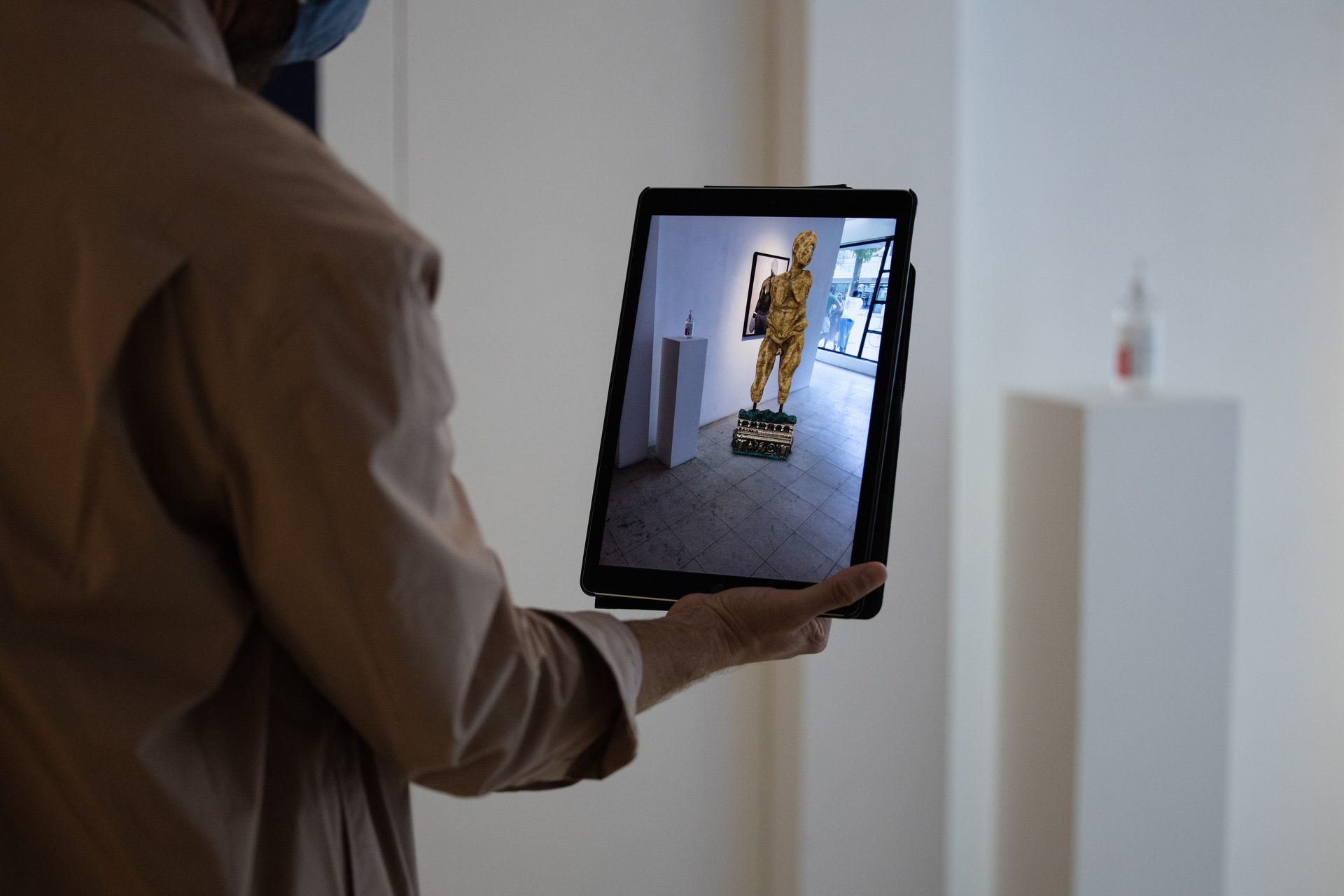 Visitor holding iPad showing AR Polyphemau figure materialized in the gallery at Art M&ucirc;r