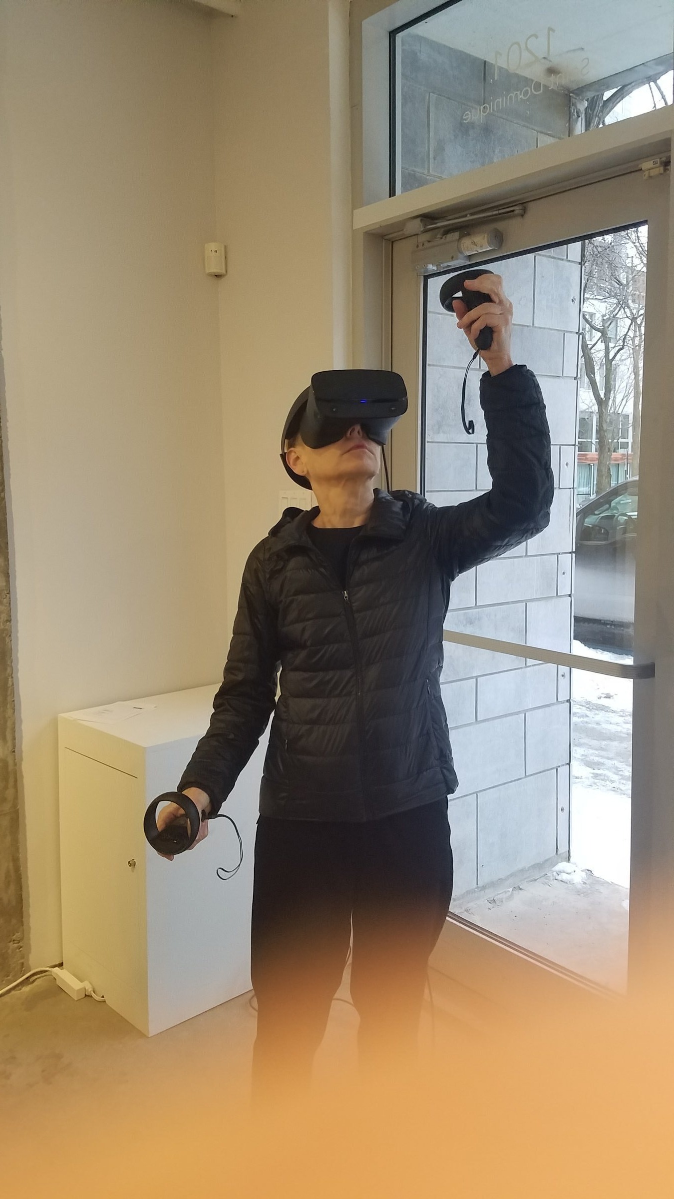 Angeline — visitor reaching upward by the gallery window, exploring the generative space