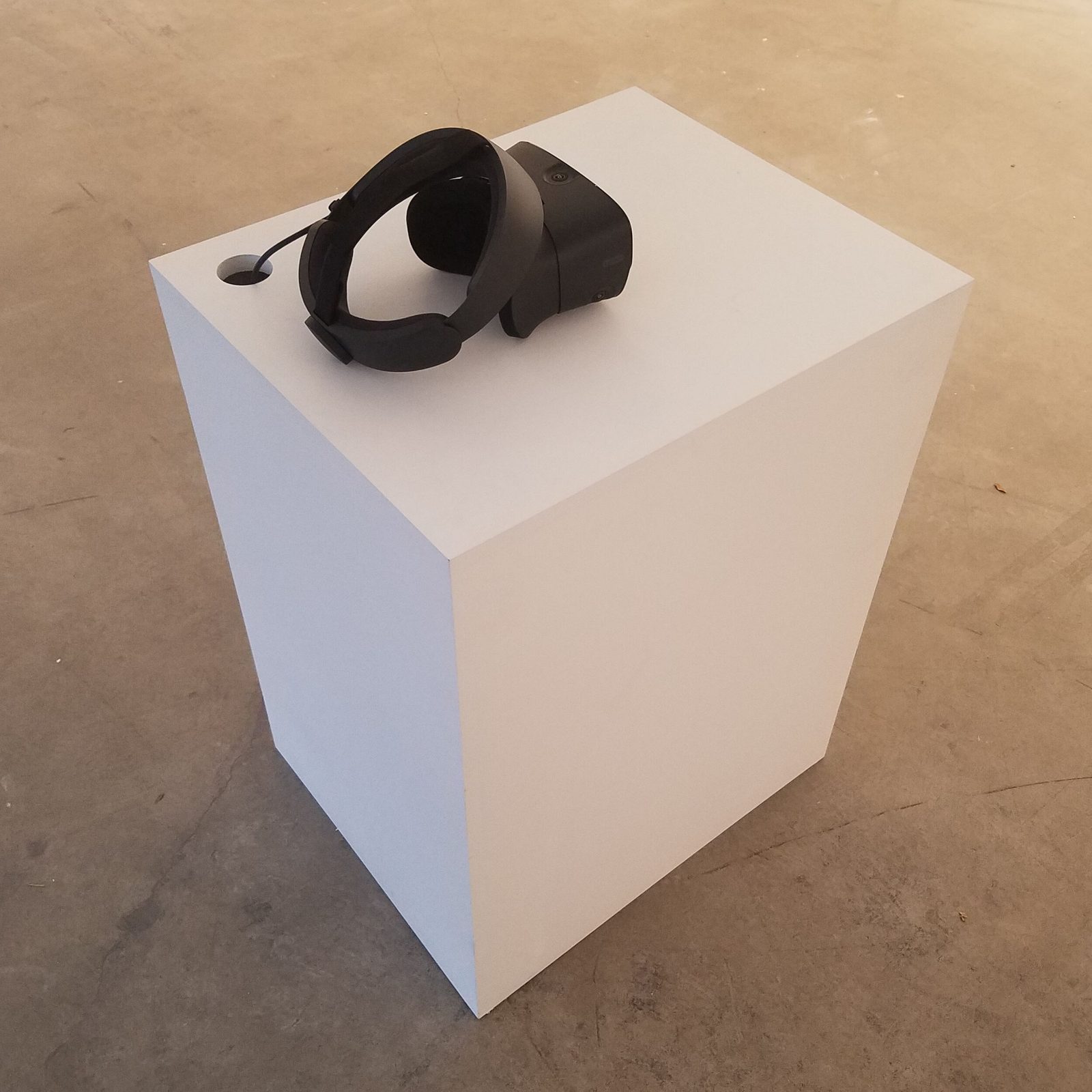 Custom VR plinth — white geometric pedestal with VR headset displayed on top, minimal gallery presentation