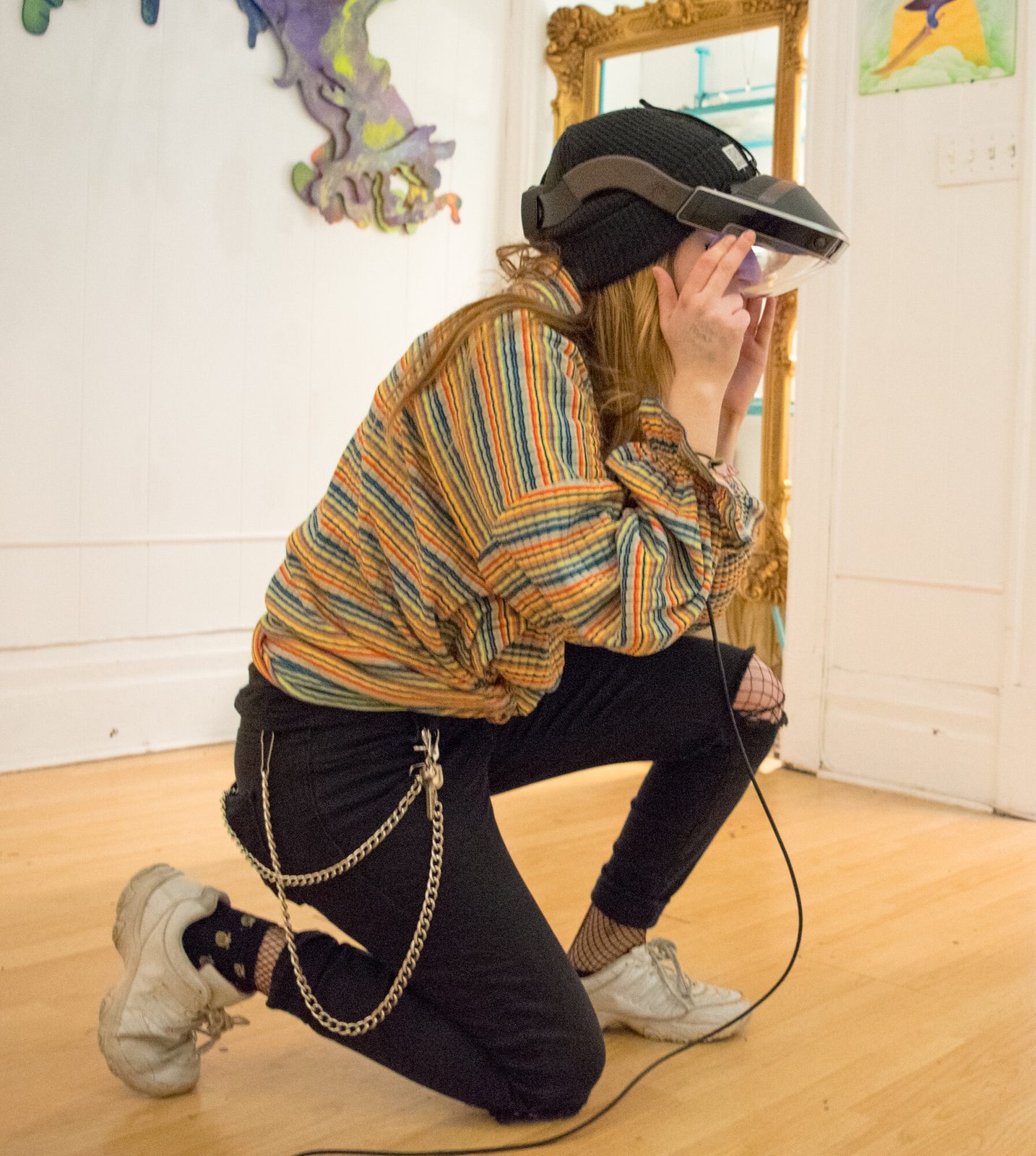Illusive Sympathy — woman wearing AR headset and gold chain, reaching toward the augmented mural, immersed in the hybrid experience
