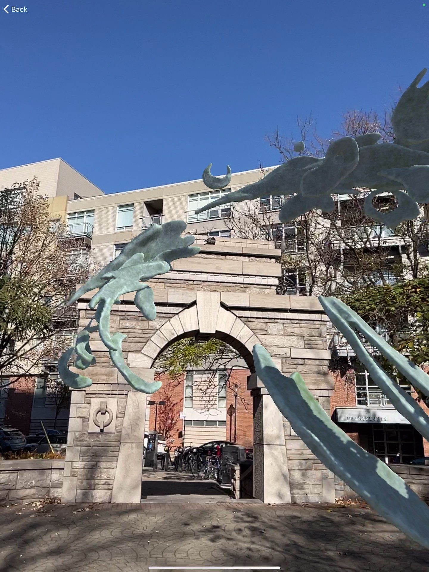 Samuel's AR sculpture — swirling metallic organic forms wrapping around the stone arch in Parc des Amériques