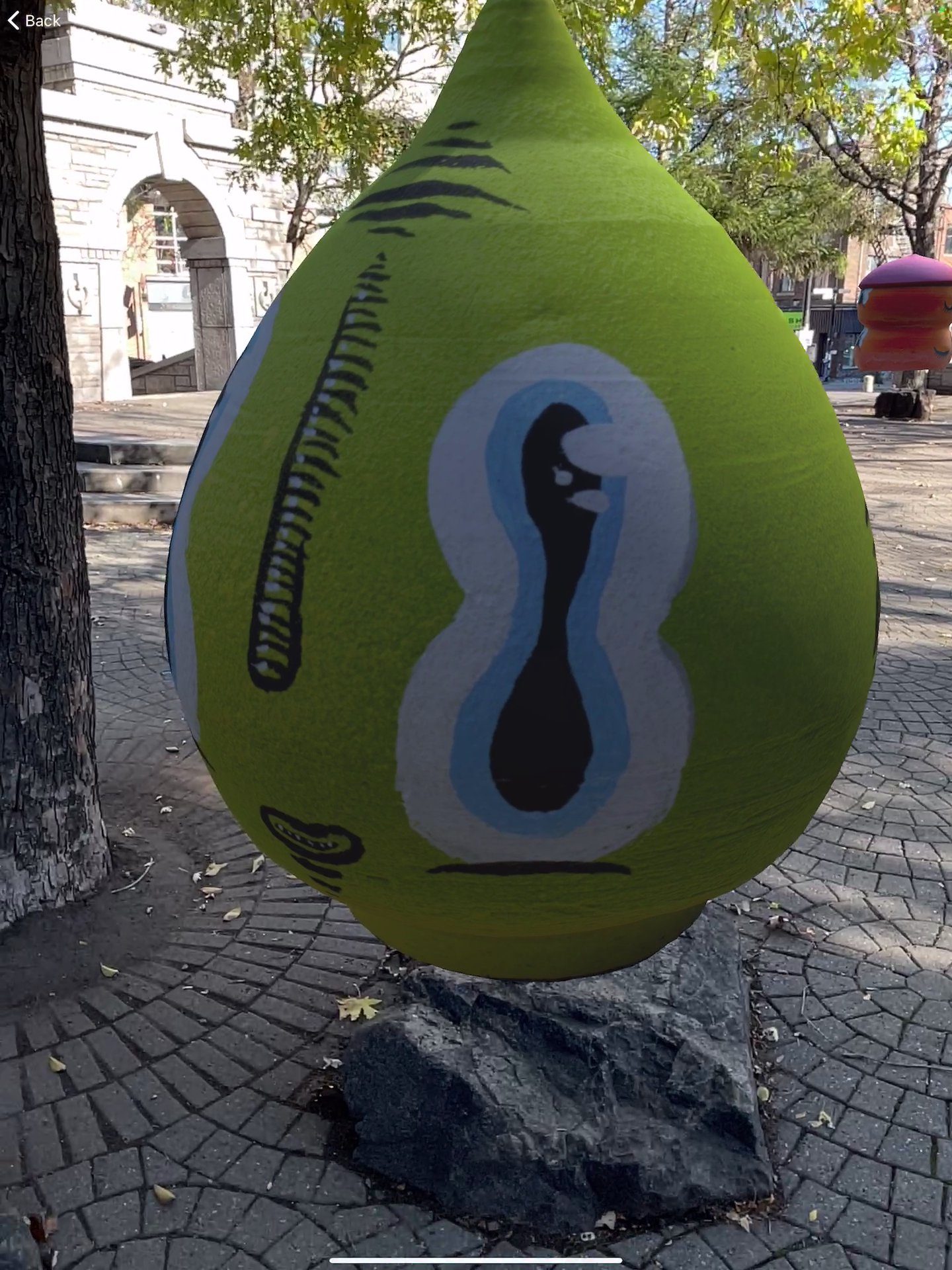 Waxhead's AR character — green teardrop shape with painted face in the park