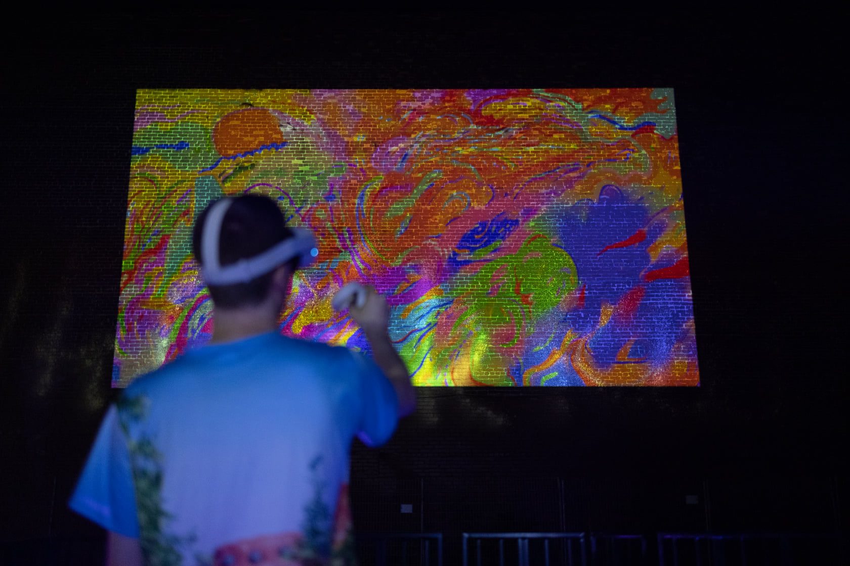 Samuel painting in VR with Kingspray, his virtual graffiti projected on the building wall behind him