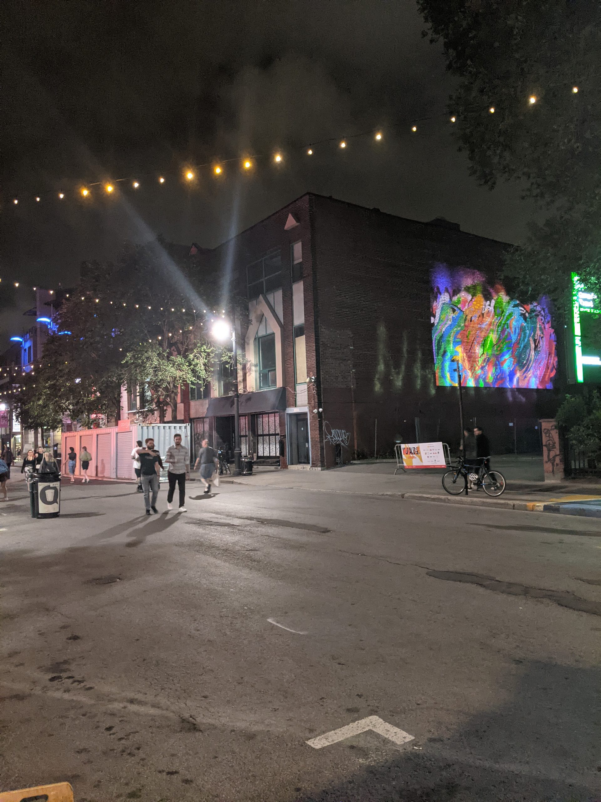 azdead's projected VR graffiti visible on building wall, boulevard Saint-Laurent at night