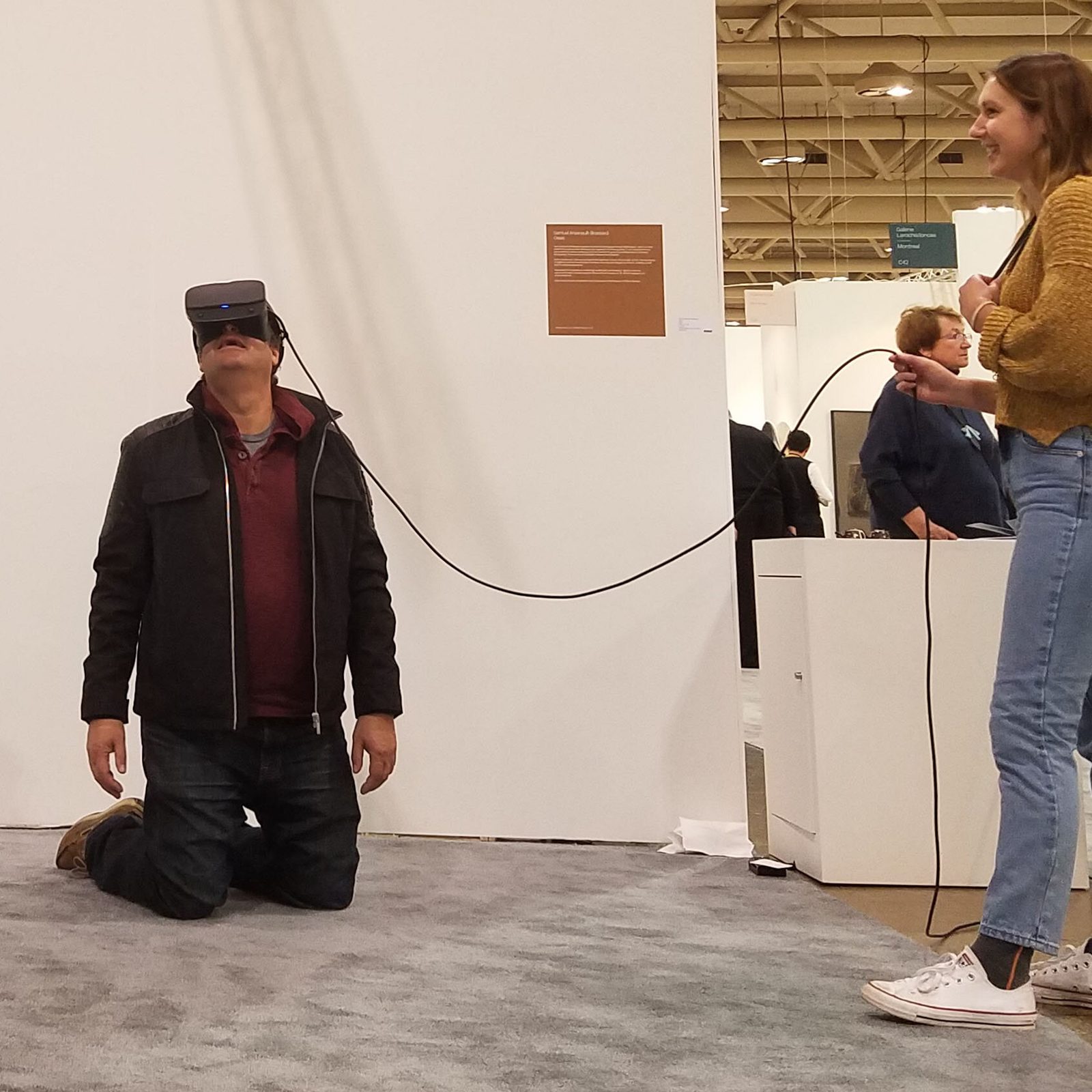 OASIS at Art Toronto — visitor kneeling in VR, art fair context visible behind the booth