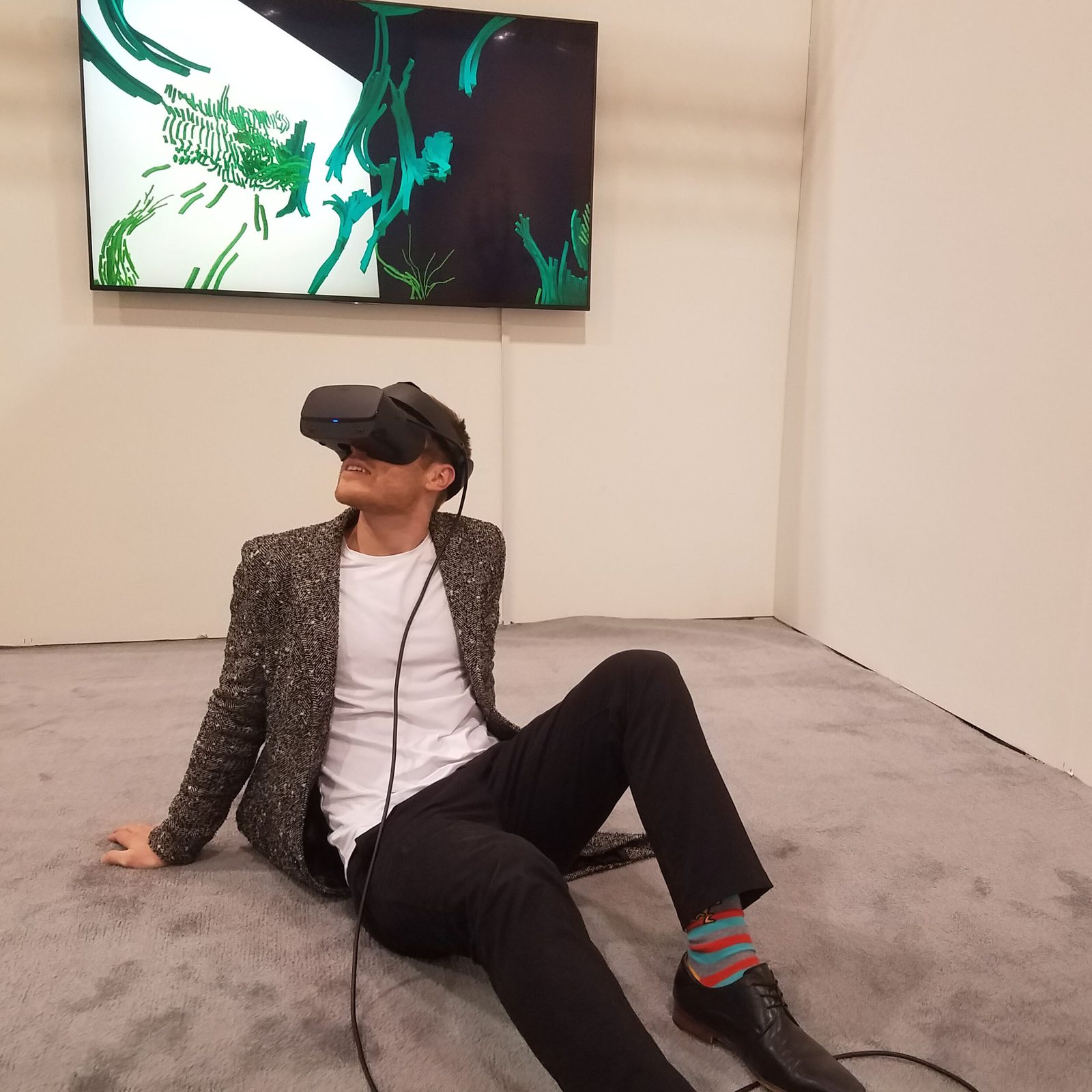 OASIS at Art Toronto — visitor sitting relaxed on the floor, leaning back slightly while experiencing the digital garden